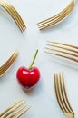 Single cherry surrounded by golden vintage forks