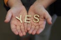 A Single Child Opening Her Hands With Wooden Letters Forming The Word Yes