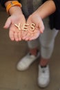 A single child opening her hands with wooden letters forming the word Yes