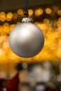 Single christmas ball hanging with lights in the background