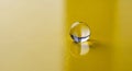 Single clear glass marble on a glossy yellow surface with reflections Royalty Free Stock Photo