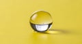 Single clear glass marble with reflections on bright yellow textured surface Royalty Free Stock Photo