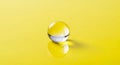 Single clear glass marble with a yellow reflection on a bright yellow surface Royalty Free Stock Photo