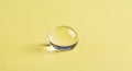 Single clear glass marble with yellow tint on a soft yellow textured surface Royalty Free Stock Photo