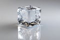 A single clear ice cube with internal bubbles reflecting light on a smooth gray surface Royalty Free Stock Photo
