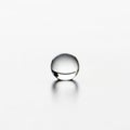 A single clear water droplet rests on a smooth light colored surface Royalty Free Stock Photo