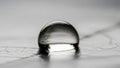 A single clear water droplet rests on a smooth slightly textured surface Royalty Free Stock Photo