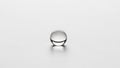 A single clear water droplet rests on a smooth white surface Royalty Free Stock Photo