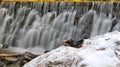 Single clog on snow pile in front of waterfall with many steps