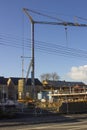 A single column cantilever style tower crane in use for the construction of private homes on a busy building site