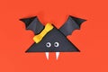 Single cute Halloween paper vampire bat with funny googly eyes and on orange background