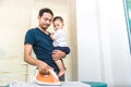 Single dad is ironing while carrying his son. People and Lifestyles concept