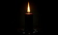 Single lit candle with dripping wax and sparks in darkness Royalty Free Stock Photo