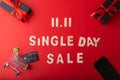 11.11 Single day sale. Black gift with red ribbon on black and red color background, Black credit card on small cart for shopping Royalty Free Stock Photo