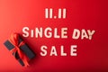 11.11Single day sale. Black gift with red ribbon and 11.11 single`s day sale text was made from wood on red color background. To Royalty Free Stock Photo