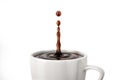 Single drop of coffee splashing into a white cup mug. Close up view