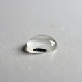 A single droplet of water rests on a smooth, white surface. The droplet is clear and Royalty Free Stock Photo