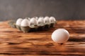 A single egg on the background of a package of eggs on a wooden table Royalty Free Stock Photo