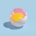 Vibrant Egg Yolk in Cracked Shell on Pastel Blue Background Royalty Free Stock Photo
