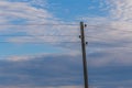 Single electricity pole with wires on the blue sky background.