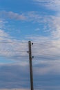 Single electricity pole with wires on the blue sky background.