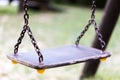 Single empty old swing on metal chain in child playground close Royalty Free Stock Photo