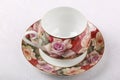 Empty porcelain tea cup with saucer and floral pattern on a table with white tablecloth Royalty Free Stock Photo