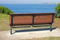 Single empty waterfront wood bench on hill with panorama of idyllic and amazing seaside landscape of bushes, distant ocean horizon