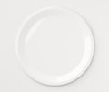 Single empty white porcelain plate on white background, flat lay top view from above