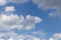 Single engine airplane flying in a cloud filled blue sky