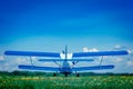 Single-engine light aircraft at the airfield, white with blue wings, in the field on the green grass against the blue sky. Royalty Free Stock Photo