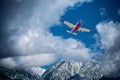 Single engine plane flying over snow capped mountain.