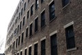 Single face of a generic urban brick apartment building with rows of windows, perspective view