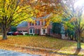 Single-family brick country house with yellow trees in the frontyard. Autumn landscape in the rays of the evening sun Royalty Free Stock Photo