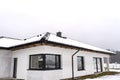 Single-family house roof covered with snow against a cloudy sky. Visible system chimney, doors, windows and falling snow. Royalty Free Stock Photo