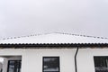 Single-family house roof covered with snow against a cloudy sky. Visible roof trusses, ventilation tile, windows and falling snow. Royalty Free Stock Photo