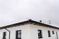 Single-family house roof covered with snow against a cloudy sky. Visible roof trusses, ventilation tile, windows and falling snow. Royalty Free Stock Photo