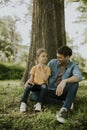 Single father sitting on grass by the tree with little daughter Royalty Free Stock Photo