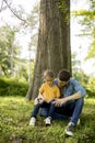 Single father sitting on grass by the tree with little daughter Royalty Free Stock Photo