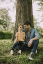 Single father sitting on grass by the tree with little daughter Royalty Free Stock Photo