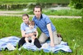 Single father and two daughters sitting on blanket on lawn in urban park, toddler kid and teenage girl, outdoor portrait Royalty Free Stock Photo