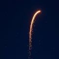 A single firework rocket ascends against a dark blue night sky, leaving a curved trail o Royalty Free Stock Photo
