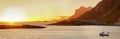 A single fishing boat on a lake with the mountains in the background at sunset with copy space. Calm, serene, tranquil Royalty Free Stock Photo