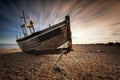 Single fishing boat stranded on pebbled beach. Dungeness, England Royalty Free Stock Photo