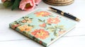 A single floral notepad styled on a white desk with a pen and subtle branding. background Royalty Free Stock Photo