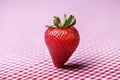 Single Fresh Strawberry Standing Up on Red Gingham Tablecloth Royalty Free Stock Photo