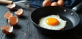 Single fried egg cooks in pan with raw eggs, shells nearby. Whisk also visible in background. Rustic scene breakfast preparation Royalty Free Stock Photo