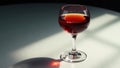 A single glass of red wine sits on a table, bathed in sunlight, casting a dramatic shadow. Generative AI Royalty Free Stock Photo
