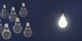 Single glowing light bulb next to group of dark bulbs over blue background, creativity, uniqueness or standing out concept Royalty Free Stock Photo