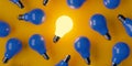 Single glowing lightbulb in group of blue bulbs over orange background, creativity, uniqueness or standing out concept Royalty Free Stock Photo